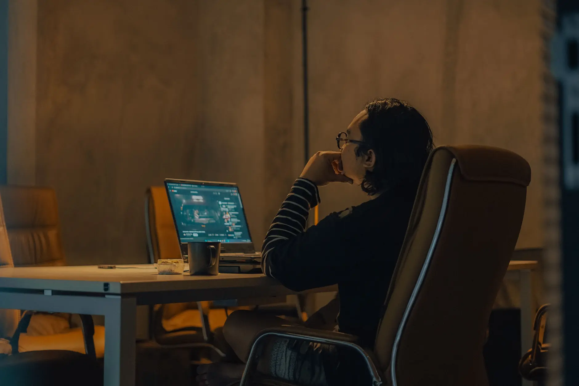 A person hunched over a laptop at an office desk demonstrating forward head posture and rounded shoulders