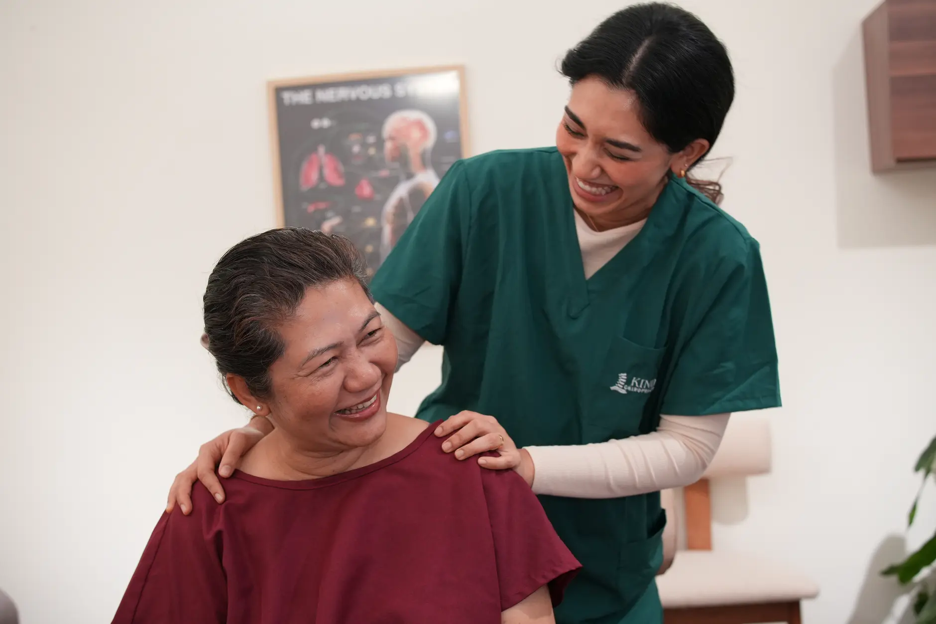 A chiropractor providing gentle, hands-on care to a relaxed, smiling older woman, demonstrating comfortable and reassuring treatment