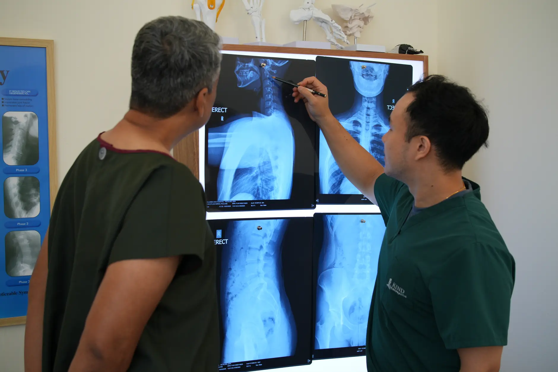 A chiropractor showing a patient their spinal X-rays on a lightbox during an assessment consultation