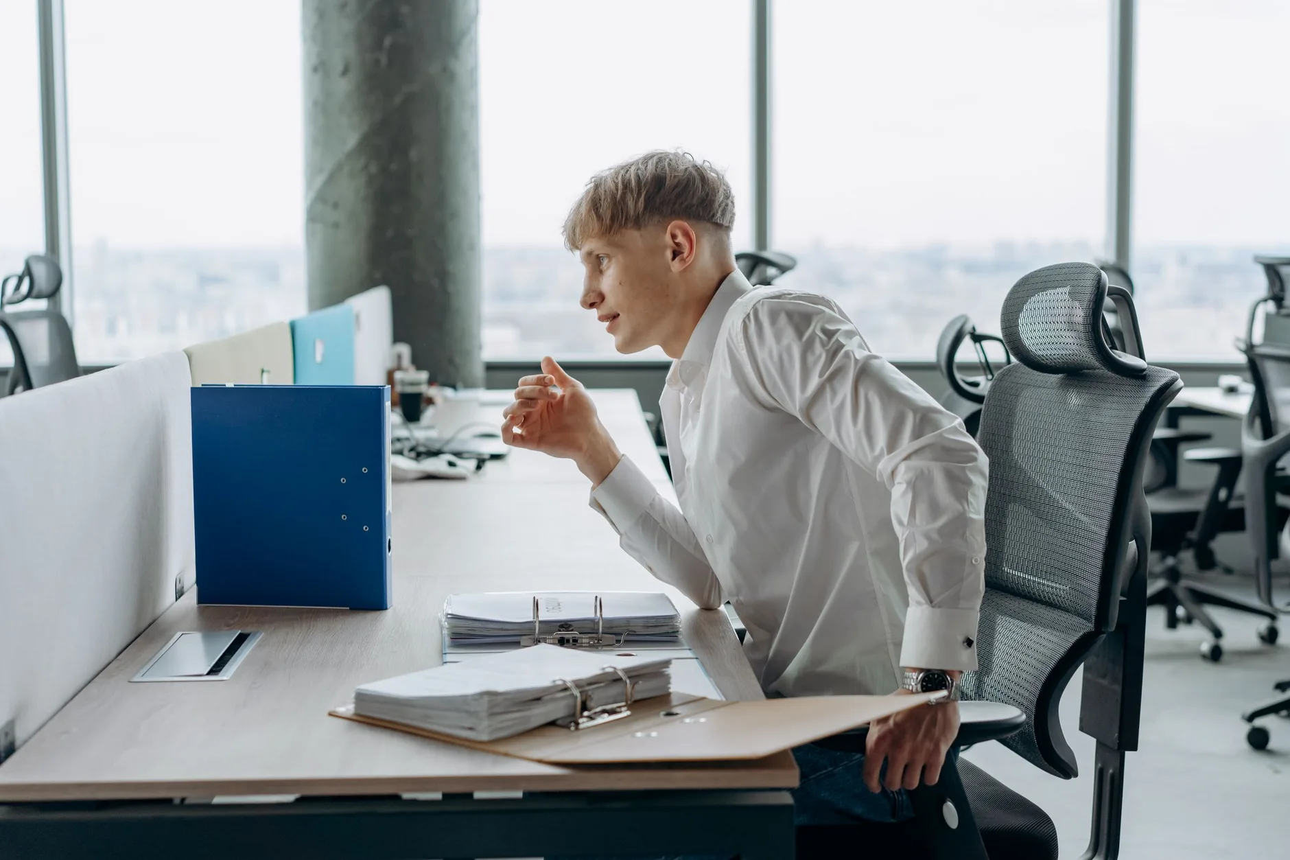 Person working at an office desk with the head leaning forward toward a screen, a common cause of neck strain
