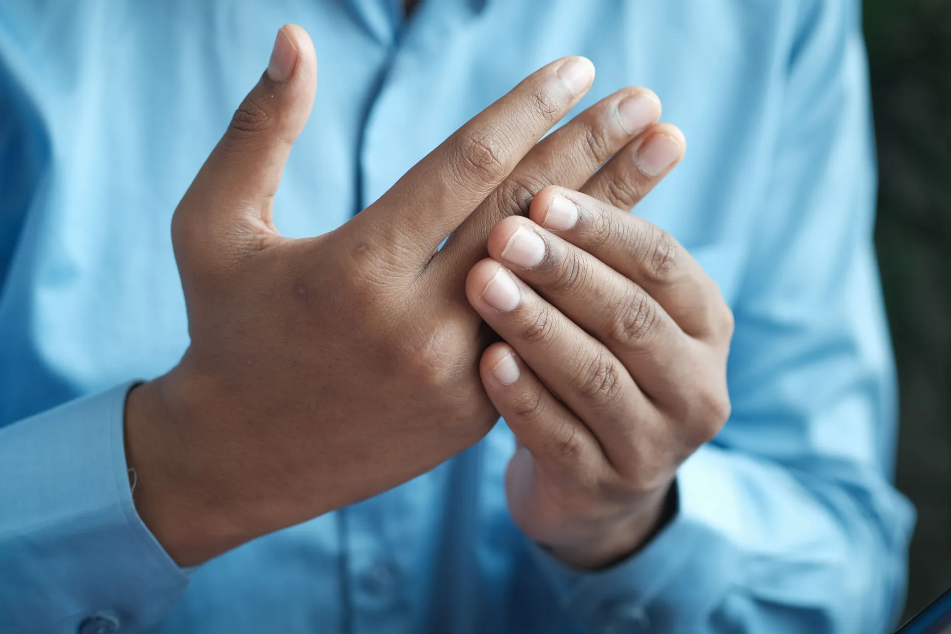A person holding their hand and wrist to relieve numbness and tingling in the fingers