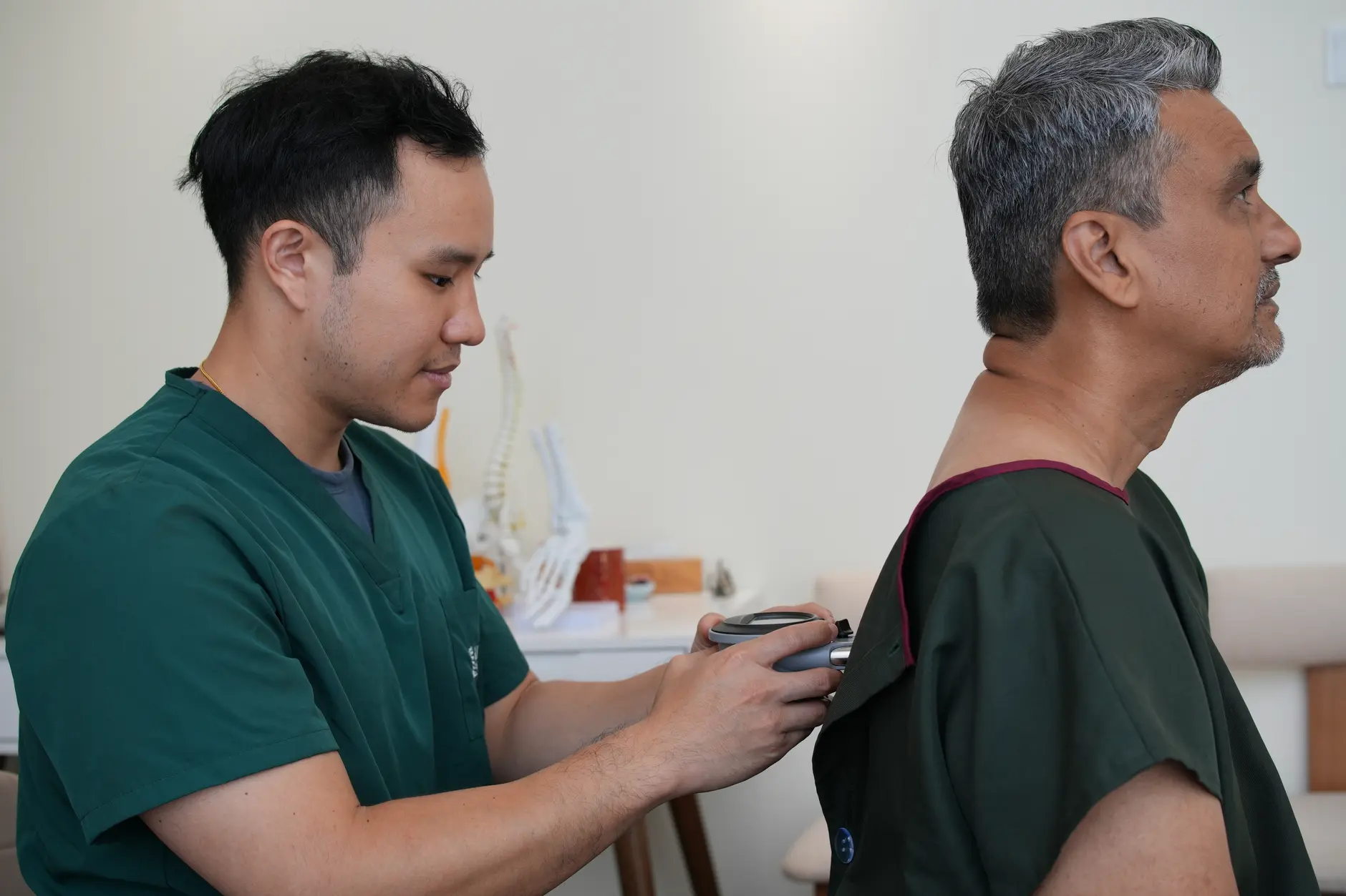 Chiropractor assessing the spine and posture of a seated patient during a slipped disc examination at Kind Chiropractic KL